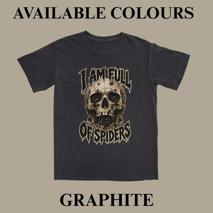 A dark charcoal gray t-shirt with a distressed graphic of a skull and the text 'I AM FULL OF SPIDERS' on the front, displayed against a solid taupe background with 'AVAILABLE COLOURS' and 'GRAPHITE' text overlays.