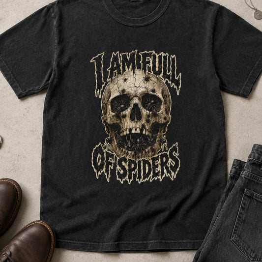 A black graphic t-shirt featuring a distressed skull design with the text 'I AM FULL OF SPIDERS' in a stylized font. The shirt is presented in a flat-lay arrangement alongside brown leather shoes, dark gray jeans, and rings on a textured concrete surface.