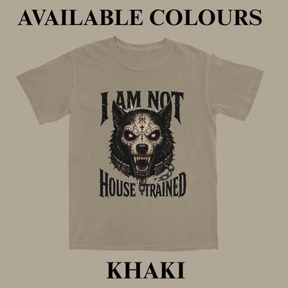 A khaki t-shirt with a black graphic of a snarling wolf and the text 'I AM NOT HOUSE TRAINED'. The image includes text overlays reading 'AVAILABLE COLOURS' at the top and 'KHAKI' at the bottom, set against a solid taupe background.