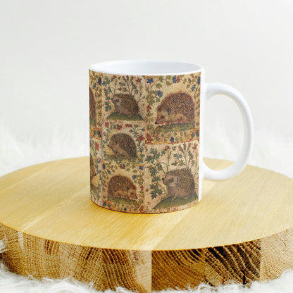 A ceramic mug featuring a medieval-style illustration of hedgehogs surrounded by floral patterns,