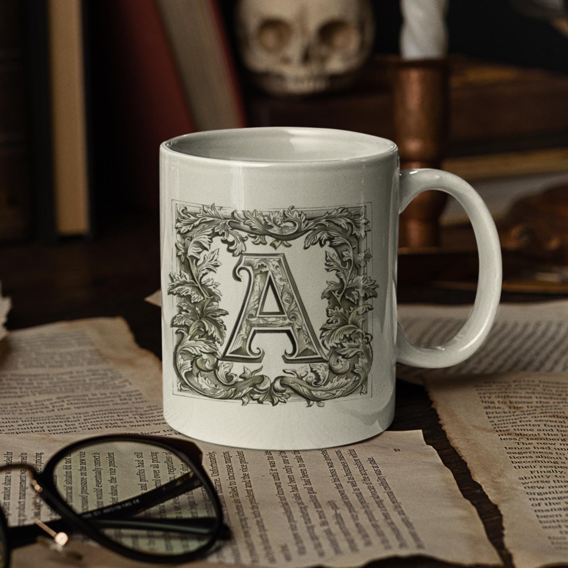 A white 11 oz mug featuring an antique-style letter  designed with intricate calligraphy and surrounded by a decorative botanical frame.