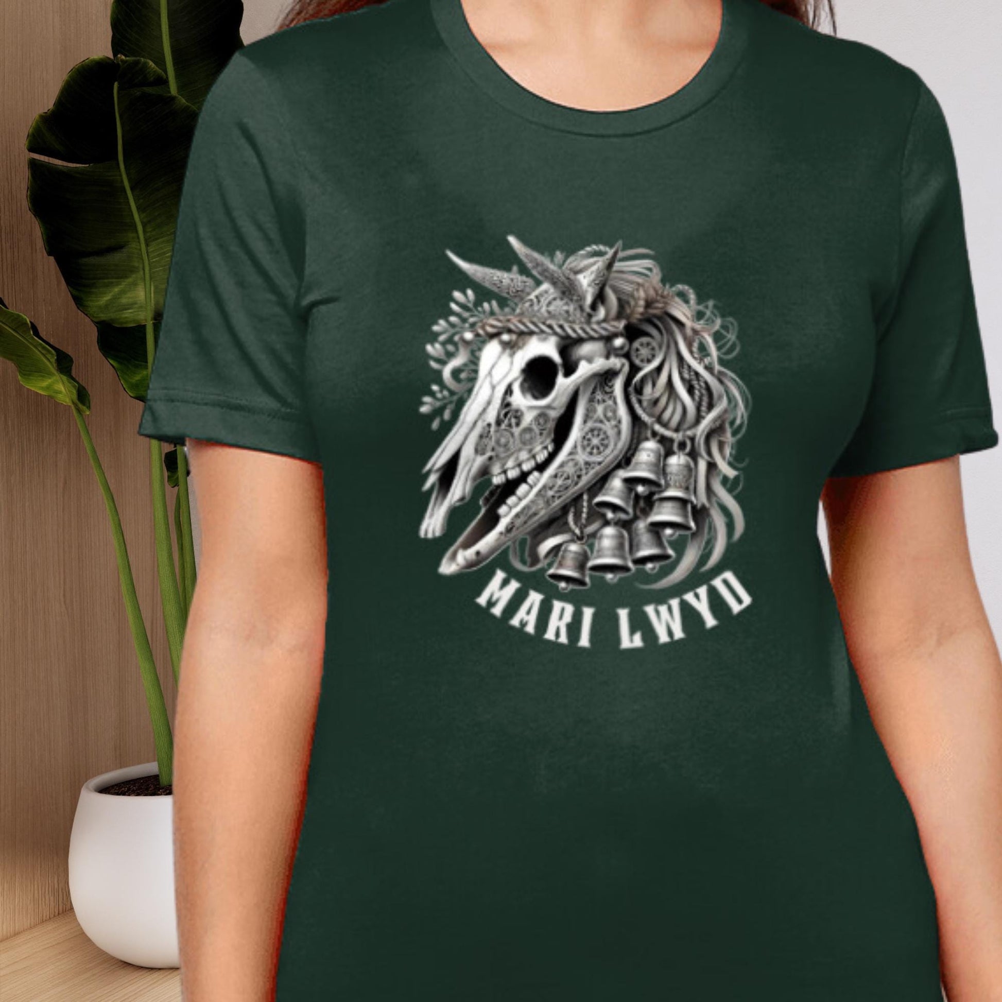 Stylized Mari Lwyd horse skull t-shirt featuring festive ribbons and bells, drawing from traditional Welsh folklore. The tee comes in black, teal, navy, or forest green, with sizes from XS to 2XL.