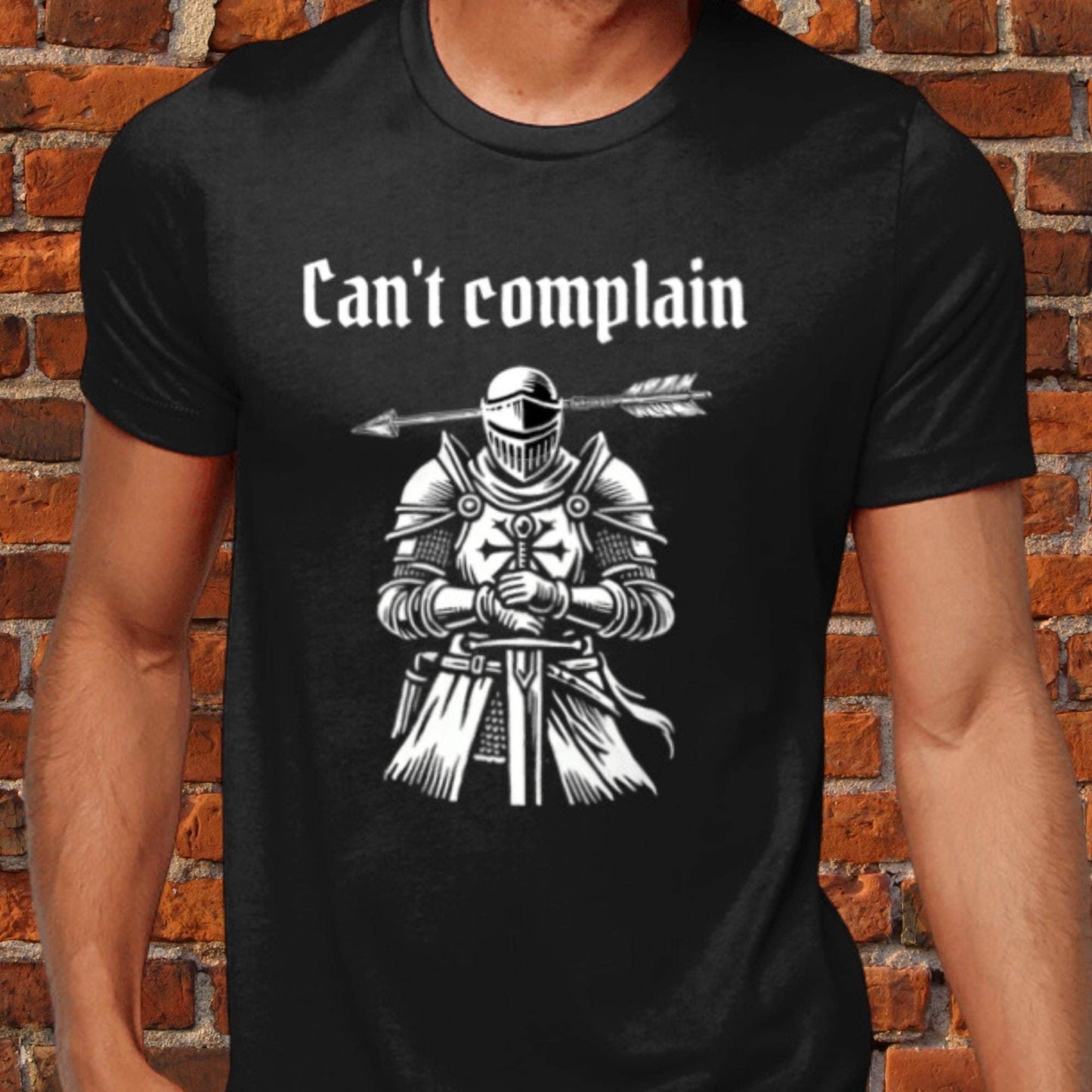 Unisex dark humour t-shirt featuring a sarcastic medieval woodcut of a knight with an arrow through his head and the phrase &quot;Can&#39;t Complain.&quot; 100% cotton, offering luxurious softness and a modern fit. Perfect for fans of quirky, gothic humour.