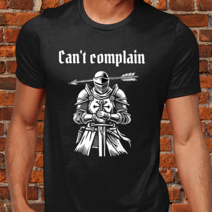 Unisex dark humour t-shirt featuring a sarcastic medieval woodcut of a knight with an arrow through his head and the phrase &quot;Can&#39;t Complain.&quot; 100% cotton, offering luxurious softness and a modern fit. Perfect for fans of quirky, gothic humour.