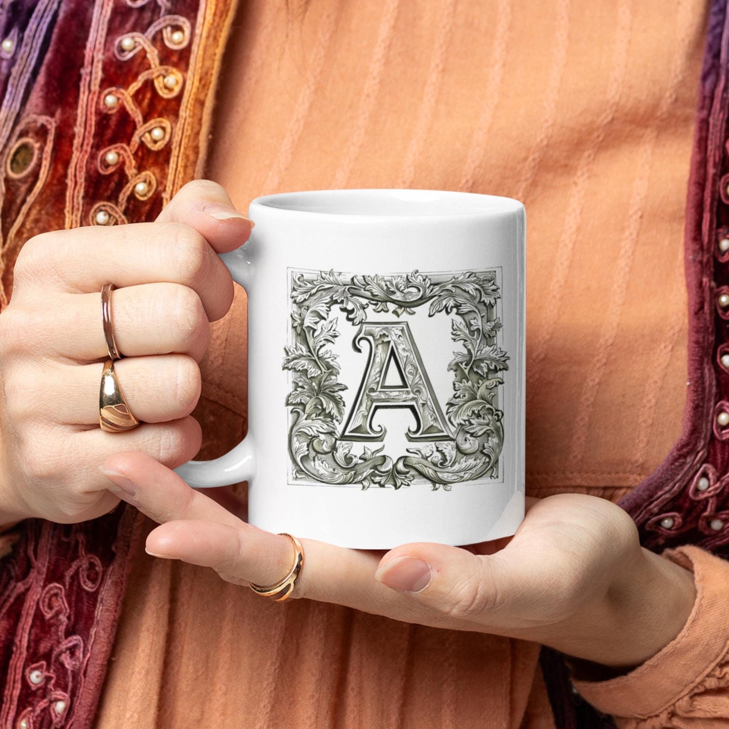Charming mug adorned with a monogram letter styled in calligraphy, framed by an ornate, manuscript-like floral border